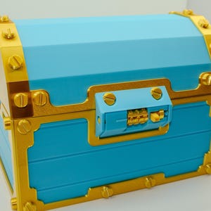 May include: A blue treasure chest with gold-colored trim and accents. The chest features a combination lock and is secured with gold-colored screws. The chest has a rectangular shape with a slightly curved top.