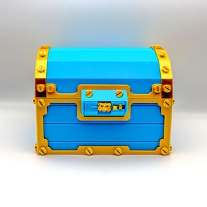 May include: A blue treasure chest with gold-colored accents. The chest features a combination lock and decorative metal bands. The chest is made of a hard material and has a rectangular shape.