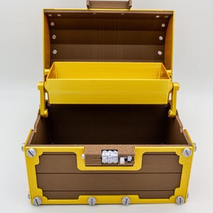 May include: An open, brown and gold treasure chest with a yellow interior. The chest features a combination lock and decorative metal accents. The lid is open, revealing a yellow tray inside.
