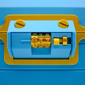 May include: Close-up of a blue and yellow combination lock. The lock features a combination dial with the numbers 467. The lock is set against a blue background, with yellow accents and screws.