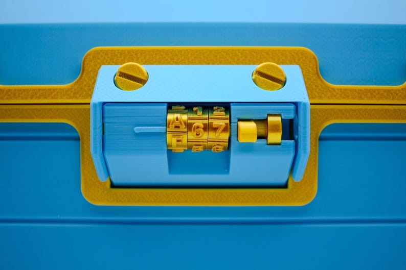 May include: Close-up of a blue and yellow combination lock. The lock features a combination dial with the numbers 467. The lock is set against a blue background, with yellow accents and screws.