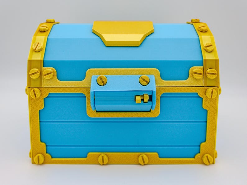 May include: A blue treasure chest with gold-colored accents. The chest features a rectangular shape with a hinged lid and a latch. Gold-colored metal bands and rivets adorn the corners and edges, adding a decorative touch. The chest is a vibrant and eye-catching decorative item.