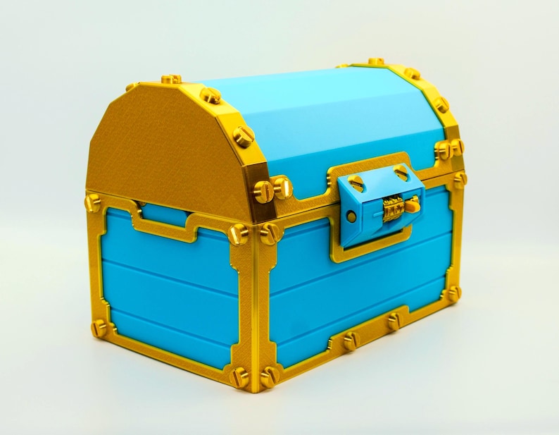 May include: A blue treasure chest with gold-colored trim and accents. The chest has a domed lid and a combination lock on the front. The chest is made of a hard material and has a smooth finish.