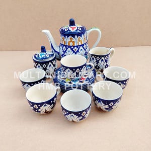 Może przedstawiać: Zestaw do herbaty z ceramiki w kolorze niebieskim i białym z misternymi wzorami kwiatowymi. Zestaw zawiera czajnik, cukiernicę, dzbanek do śmietanki i sześć filiżanek i spodków.