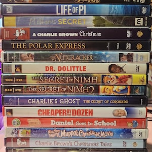 May include: A stack of 17 DVD cases featuring various movie titles, including "The Sound of Music", "Life of Pi", "The Polar Express", "Dr. Dolittle", "The Secret of Nimh", "Charlie's Ghost", "Cheaper by the Dozen", "Daniel Goes to School", "It's a Very Merry Muppet Christmas Movie", "Charlie Brown's Christmas Tales", "Sinbad: Legend of the Seven Seas", "Dr. Seuss' Horton Hears a Who!" and "Open Season 3".