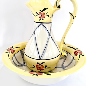May include: A vintage ceramic pitcher and basin set. The pitcher is yellow with a white diamond pattern and floral accents. The basin is also yellow with floral designs. The set is a decorative item.