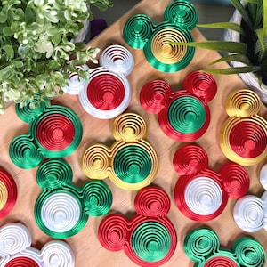 May include: A collection of three-dimensional mouse-shaped ornaments featuring concentric circular patterns. These items are crafted in metallic red, green, gold, and white finishes, displaying a layered, tiered design across the surface.