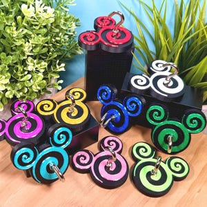 May include: A collection of mouse-shaped hooks featuring spiral patterns in various colors including red, yellow, pink, blue, green, and white. Each hook has a black base and a metallic silver-toned metal hook attached to the center of the spiral design.
