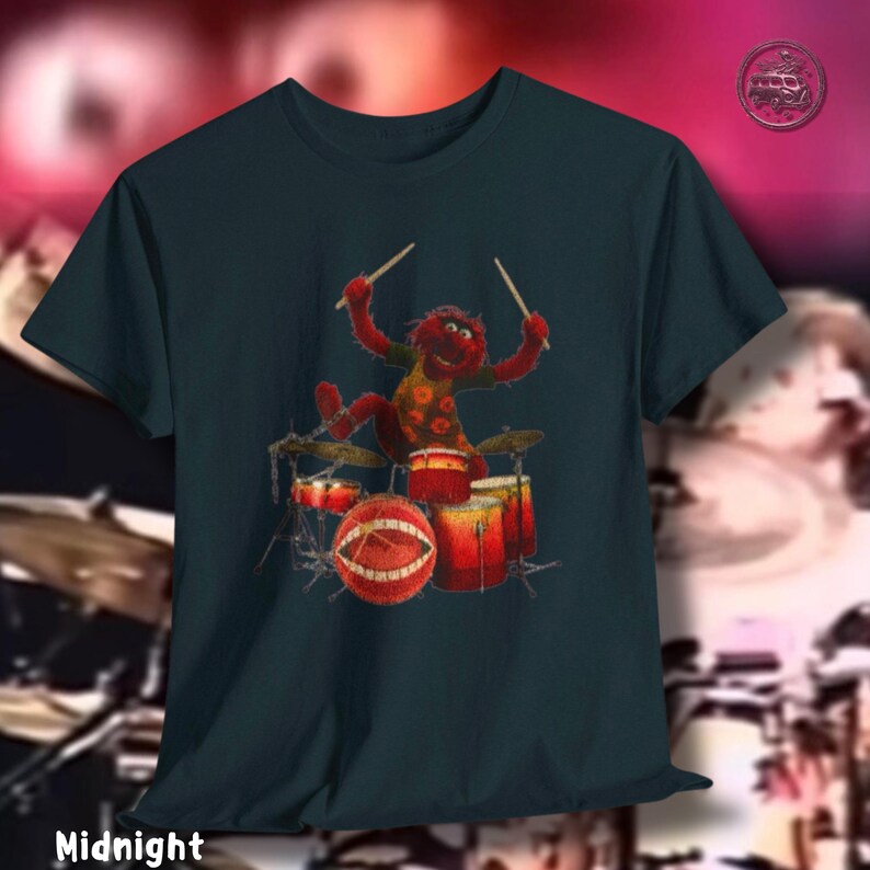 K&ouml;nnte beinhalten: Nachtblaues T-Shirt mit einem Cartoon-Schlagzeuger in Rot und Gelb. Das Schlagzeug ist rot und orange. Das Wort "Midnight" ist unten auf dem Shirt aufgedruckt.