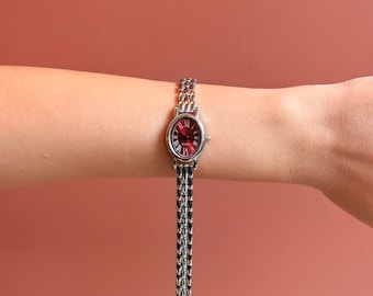 Reloj vintage para mujer con esfera romana ovalada y correa de metal de cuarzo, diseño elegante.