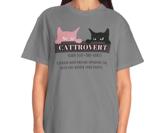 May include: Grey t-shirt featuring the word "CATTROVERT" and its definition. The design includes a pink and a black cat. The text below defines "CATTROVERT" as a person who prefers spending time with cats rather than people.