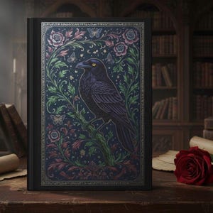 May include: A black journal with a detailed illustration of a raven perched on a branch, surrounded by floral and butterfly motifs. The cover has a dark blue background with gold accents and a decorative border. A red rose is on the wooden surface.