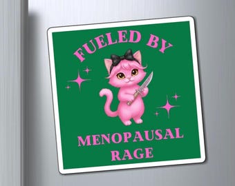 Op de afbeelding: Een vierkante magneet met een donkergroene achtergrond met een roze cartoonkat die een zwarte strik draagt en een klein mes vasthoudt. De tekst FUELED BY MENOPAUSAL RAGE staat in roze hoofdletters, geaccentueerd door kleine roze vierpuntige sterren.