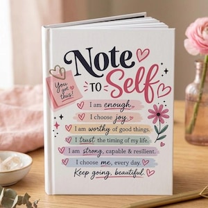 May include: A white hardcover journal with the title Note to Self in dark blue and pink script. The cover features a pink sticky note graphic with the text You got this and five colorful horizontal bars with affirmations and small heart icons.