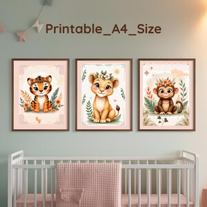 Può includere: Tre stampe artistiche incorniciate con adorabili cuccioli di animali: una tigre, un cucciolo di leone e una scimmia, ognuno adornato con dettagli floreali. Le stampe sono ambientate su uno sfondo pastello tenue, con il testo "Printable_A4_Size" sopra. L'opera d'arte è esposta sopra una culla bianca.