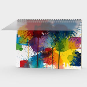 Könnte beinhalten: Ein spiralgebundenes Notizbuch mit einem farbenfrohen Aquarell-Spritzdesign. Das Kunstwerk zeigt leuchtende Farbtöne von Gelb, Blau, Rot, Grün und Lila und erzeugt so eine dynamische und künstlerische Optik. Das Notizbuch hat einen transparenten Kunststoffeinband.