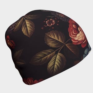 May include: A black beanie featuring a dark floral pattern with deep red roses, muted green leaves, and small accent flowers. The fabric displays a repeating botanical print across the entire surface of the headwear, showcasing a contrast between the dark background and the rich, warm tones of the floral elements.