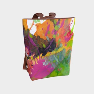 Puede incluir: Una mochila de cuero marrón con un diseño abstracto colorido con salpicaduras de pintura rosa, naranja, amarilla, verde y azul.