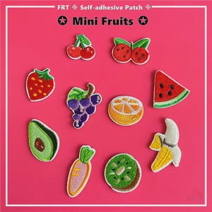 Pode incluir: Uma coleção de patches autocolantes com mini frutas bordadas. Os patches incluem um morango, uvas, uma fatia de laranja, uma fatia de melancia, um abacate, uma cenoura, um kiwi, uma banana e cerejas. O texto "Mini Fruits" é exibido em um fundo rosa.