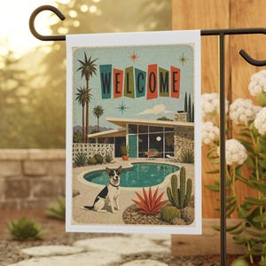 May include: A rectangular garden flag featuring a mid-century modern house with a swimming pool, palm trees, and cacti. A black and white dog sits near the pool. The word WELCOME is printed in large, colourful, stylised letters at the top.