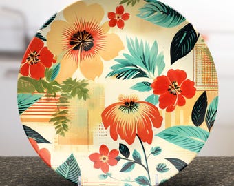 Può includere: Un piatto decorativo con un design floreale. Il piatto presenta grandi fiori arancioni e rossi, foglie turchesi e uno sfondo color crema. Il piatto è esposto su un supporto trasparente, mostrando i suoi colori vivaci e i dettagli intricati.