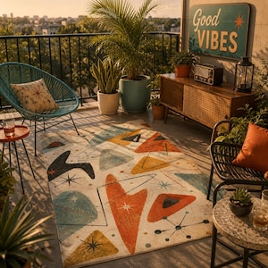 May include: A rectangular area rug featuring a cream background with a repeating pattern of orange, yellow, teal, and black geometric shapes, including boomerangs, triangles, and starbursts, laid out on a balcony with outdoor furniture.
