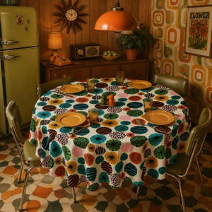 May include: A round dining table set for a meal, featuring a colorful floral patterned tablecloth with yellow plates, clear glasses, and green chairs. The retro-style kitchen includes a green refrigerator and a vintage clock.