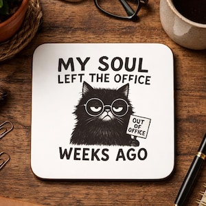 Op de afbeelding: Een vierkante witte onderzetter met een zwarte illustratie van een pluizige kat met een ronde bril. De kat houdt een bordje vast met de tekst OUT OF OFFICE. De tekst boven en onder de kat luidt MY SOUL LEFT THE OFFICE WEEKS AGO in het zwart.