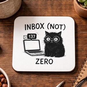 May include: Square white coaster with a black cat wearing glasses, a laptop, and the text "INBOX (NOT) ZERO". The cat has a worried expression. A speech bubble shows 137 unread emails.