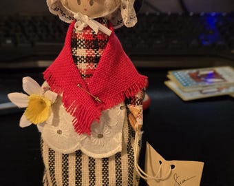 Muñeca vintage de taller artesanal galés, confeccionada en auténtica tela galesa, que sostiene un narciso. Presentación artesanal de la industria local. Artículo para estante de baratijas.