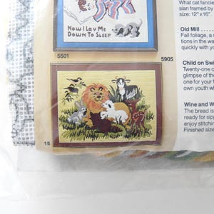 May include: A package of cross-stitch kits featuring two framed designs. One depicts a lion, lamb, and other animals. The other shows a cat and the text "Now I Lay Me Down To Sleep". The kits are for embroidery.