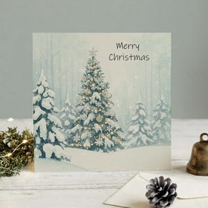 May include: A square greeting card featuring a watercolor illustration of a snow-covered forest with a central decorated Christmas tree. The text Merry Christmas is printed in black. A brass bell and a pinecone sit on the surface nearby.