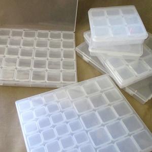 May include: A set of clear plastic storage boxes with multiple compartments. The boxes are stacked on top of each other and are ideal for organizing small items.