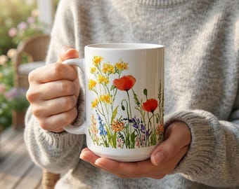 May include: A white ceramic mug with a black handle and the text "But First, Coffee" in a bold, black font. The mug is set against a blurred background, suggesting a cozy setting.