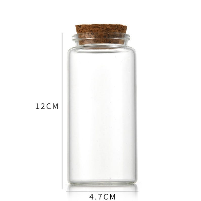 Może przedstawiać: Przezroczysta szklana butelka z korkowym korkiem. Butelka ma 12 cm wysokości i 4,7 cm szerokości.