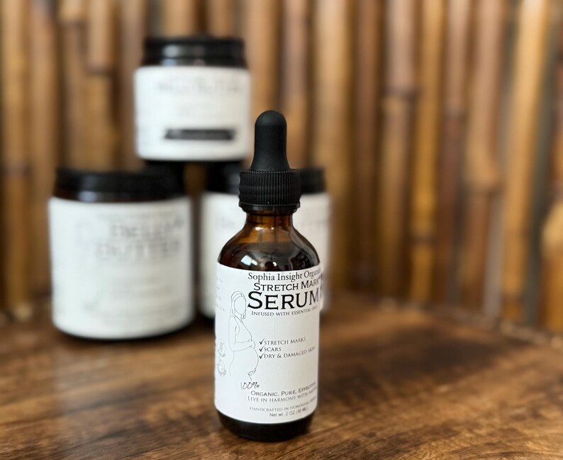 May include: A brown glass serum bottle with a black dropper, labeled "Sophia Insight Organic Stretch Mark Serum." The label also features an illustration of a woman. Several jars are stacked in the background.
