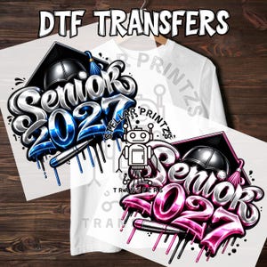 May include: Two DTF transfers featuring the text Senior 2027 in a metallic graffiti style. One design uses blue accents with a graduation cap and pen, while the other uses pink accents. Both include a robot logo and the text Stellar Printz.