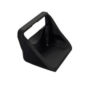 Könnte beinhalten: Ein schwarzes, eckiges Objekt mit einem Griff, möglicherweise ein Behälter oder Halter. Das Objekt hat eine strukturierte Oberfläche und ein geometrisches Design. Der Griff ist rechteckig und scheint aus einem ähnlichen Material wie der Rest des Objekts zu bestehen.