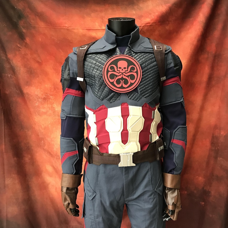May include: A tactical costume featuring a dark blue and red jacket with a high collar, a circular red and black Hydra emblem on the chest, white abdominal armor plating, brown utility straps, and brown gloves on a mannequin torso.