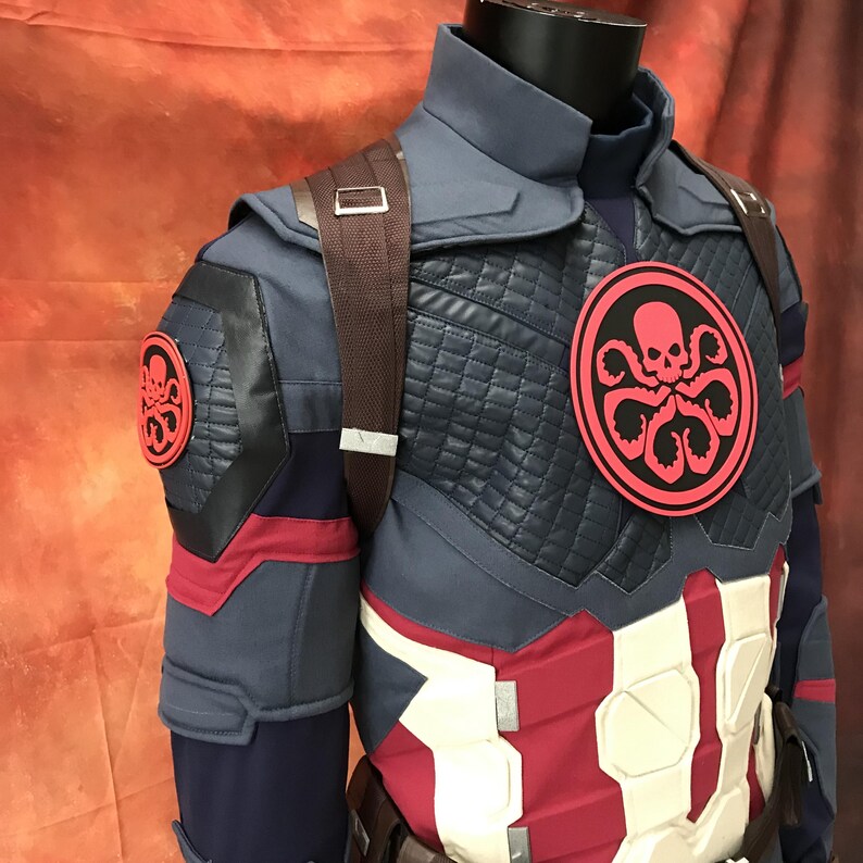 May include: A blue, red, and white tactical costume jacket featuring a quilted chest panel, a high collar, and brown shoulder straps. A circular red and black Hydra logo with a skull and tentacles is centered on the chest and on the right shoulder.