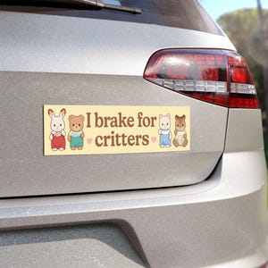 Może przedstawiać: Prostokątna naklejka na zderzak z napisem "I brake for critters" w brązowej czcionce na jasnym ż&oacute;łtym tle. Naklejka zawiera ilustracje kresk&oacute;wkowe kr&oacute;lika, misia, kota i wiewi&oacute;rki.