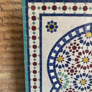Puede incluir: Un panel de mosaico con un dise&ntilde;o geom&eacute;trico. El panel presenta un fondo blanco con azulejos azules, rojos, amarillos y verdes. El borde es turquesa. El dise&ntilde;o incluye estrellas y patrones arqueados.