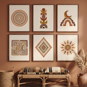 May include: A set of six framed wall art prints featuring geometric and celestial motifs in shades of terracotta, mustard yellow, black, and white. The designs include concentric circles, stacked shapes, a crescent moon, a sun, and patterns.
