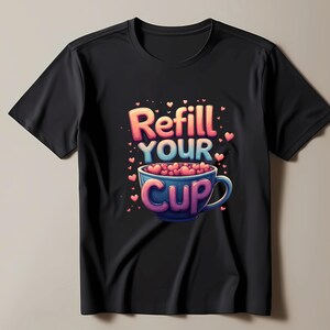 May include: Black t-shirt with a vibrant graphic. The design shows the words "Refill Your Cup" above a blue teacup filled with pink hearts. Small pink hearts are scattered around the cup and text.