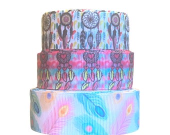 Può includere: Tre rotoli di nastro colorato con un motivo di acchiappasogni e piume. Il nastro è rosa, blu e bianco con una varietà di colori nel motivo.