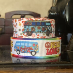 Puede incluir: Dos rollos de cinta blanca con un borde de arcoíris. La cinta presenta una camioneta vintage con signos de paz y las palabras "Peace Love" impresas en ella.