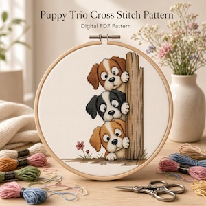 May include: A circular wooden embroidery hoop containing a cross stitch pattern of three puppies peeking from behind a wooden post. The text Puppy Trio Cross Stitch Pattern Digital PDF Pattern is visible. The design features brown and black dogs.