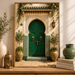 May include: A framed wall art print depicting a green arched door with intricate gold hardware, flanked by two potted olive trees. The scene features ornate tile work, hanging greenery, and a lantern, all set within a light-coloured stone structure.