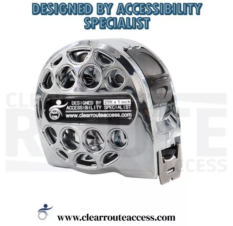 May include: A chrome tape measure with a perforated design. The text on the tape measure reads "DESIGNED BY ACCESSIBILITY SPECIALIST" and "DESIGNED BY 25ft x 1 inch ACCESSIBILITY SPECIALIST". The website www.clearrouteaccess.com is also visible.