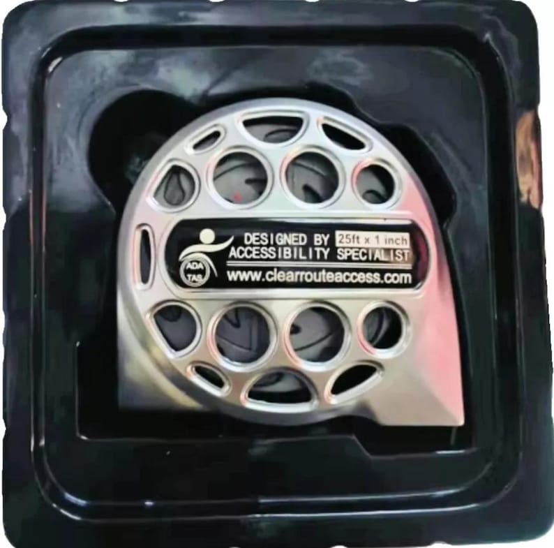 May include: A silver-colored measuring device with multiple circular openings, packaged in a black plastic container. The device has a label that reads "DESIGNED BY 25ft x 1 inch ACCESSIBILITY SPECIALIST www.clearrouteaccess.com".